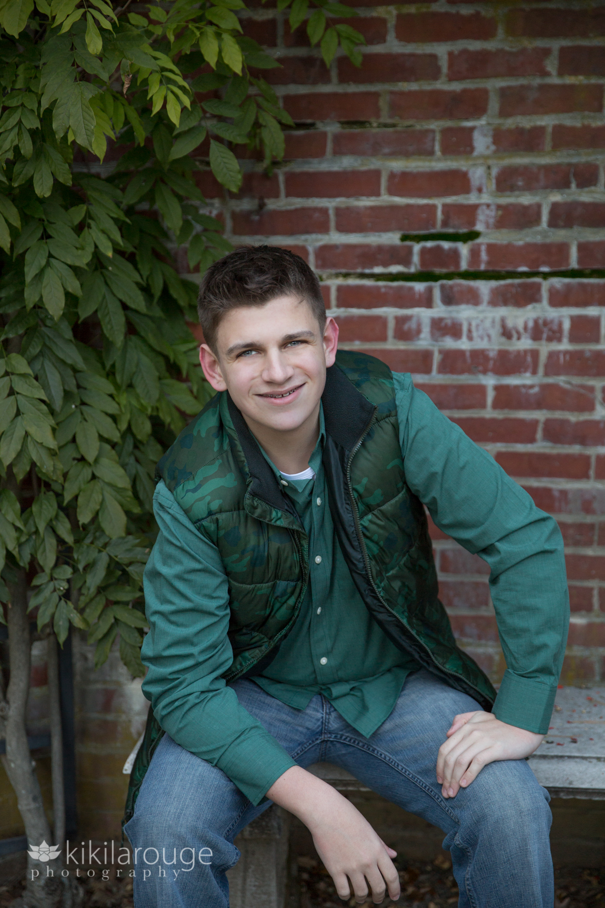 Senior Portrait boy in camouflage vest by barn