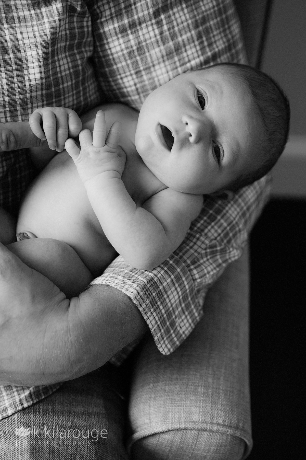 Newborn baby looking at camera cradled Dad's arms