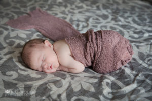 Baby sleeping on gray bed