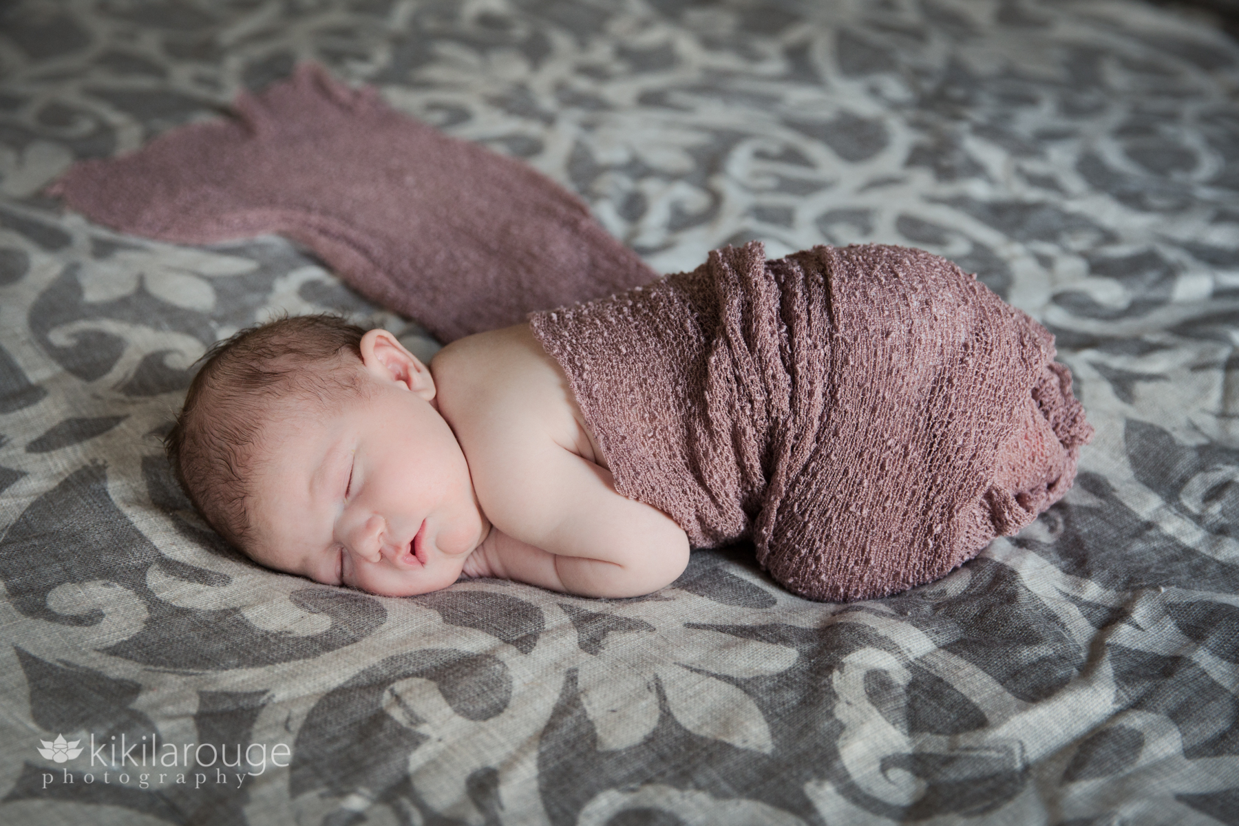 Baby sleeping on gray bed