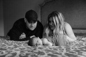 Newborn baby sleeping on parents bed with Mom and Dad