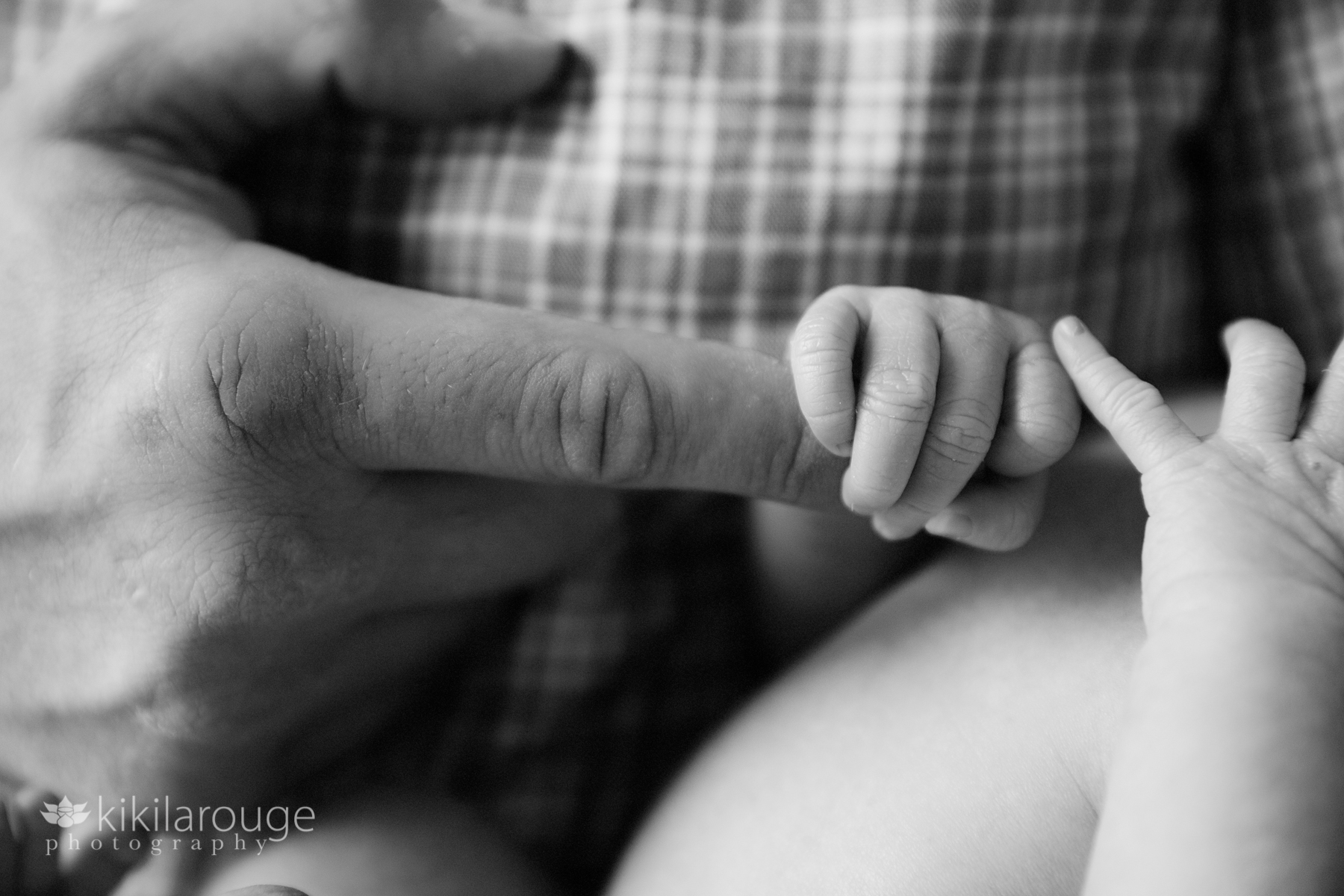 Newborn baby holding Dad's finger