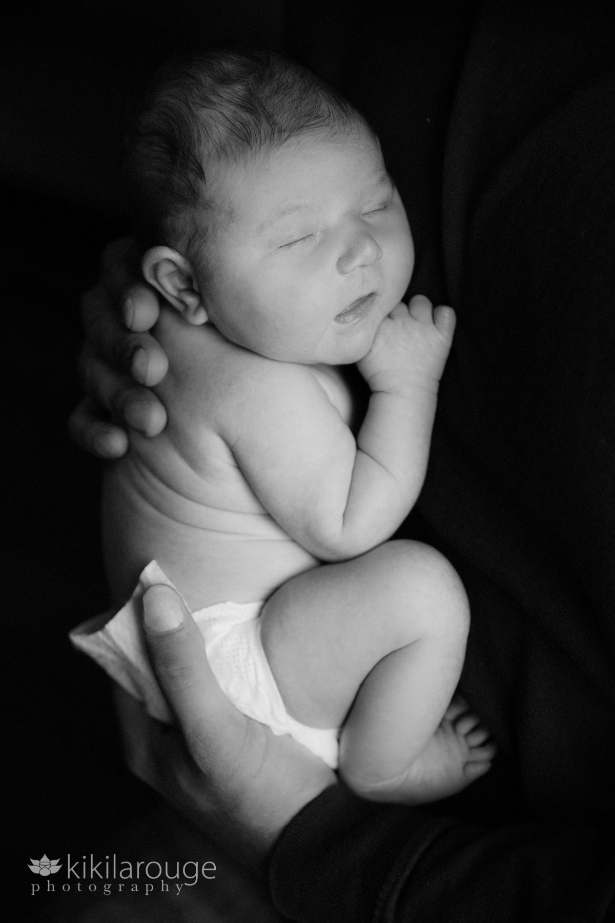 Newborn baby portrait sleeping in Dad's arms