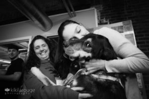 Two women snuggling cute black rescue dog
