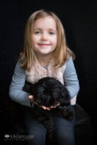 Little girl holding her black dog