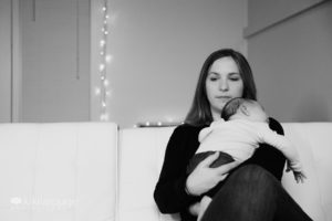 Mom sitting on couch with baby sleeping on shoulder