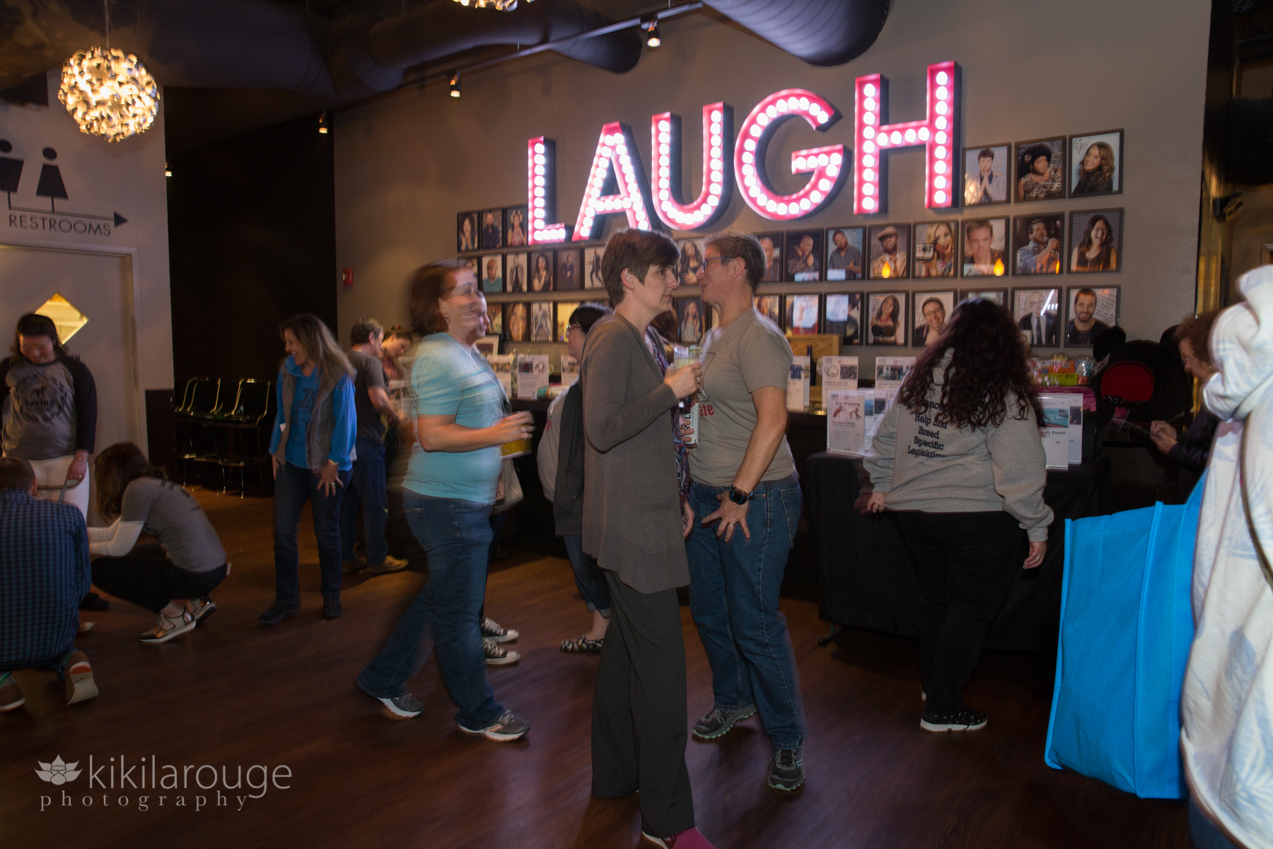 People mingling and bidding on Silent Auction in front of Laugh sign