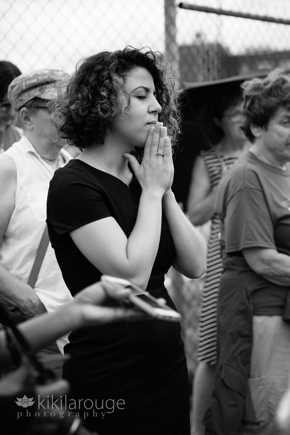 Women eyes closed in prayer at ICE vigil