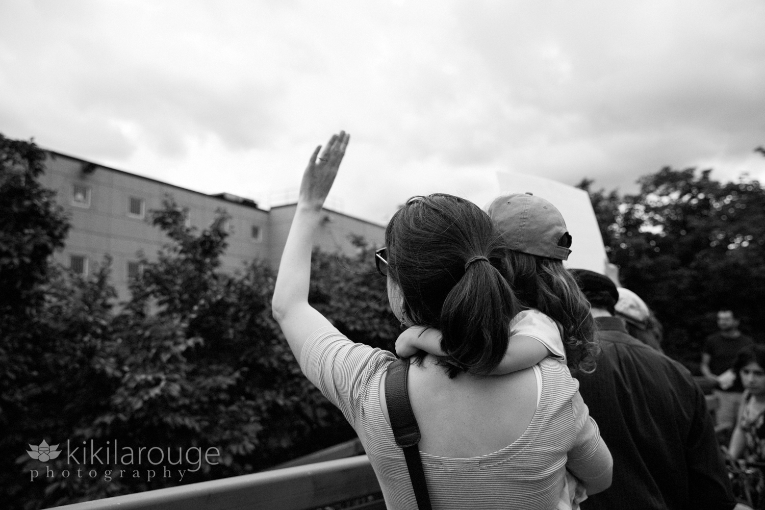 Woman with her young daughter waving at ICE detainees in Boston