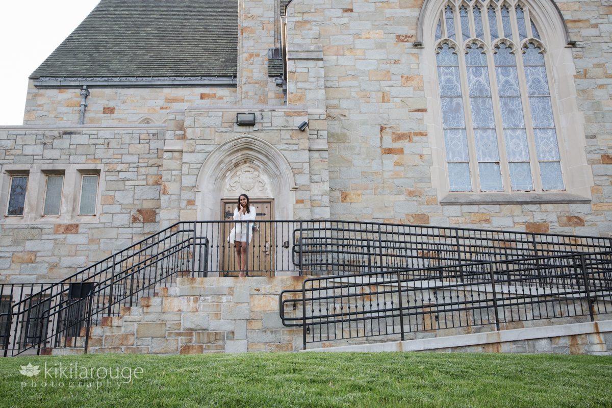 Girl in white dress in front of large stone church Boston College