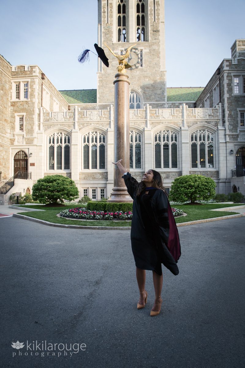 Woman throwing cap at graduation in front of BC monument