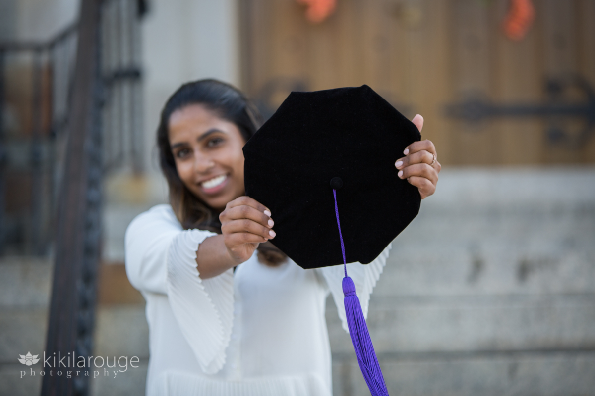 Woman holding graduation cap with purple tassel