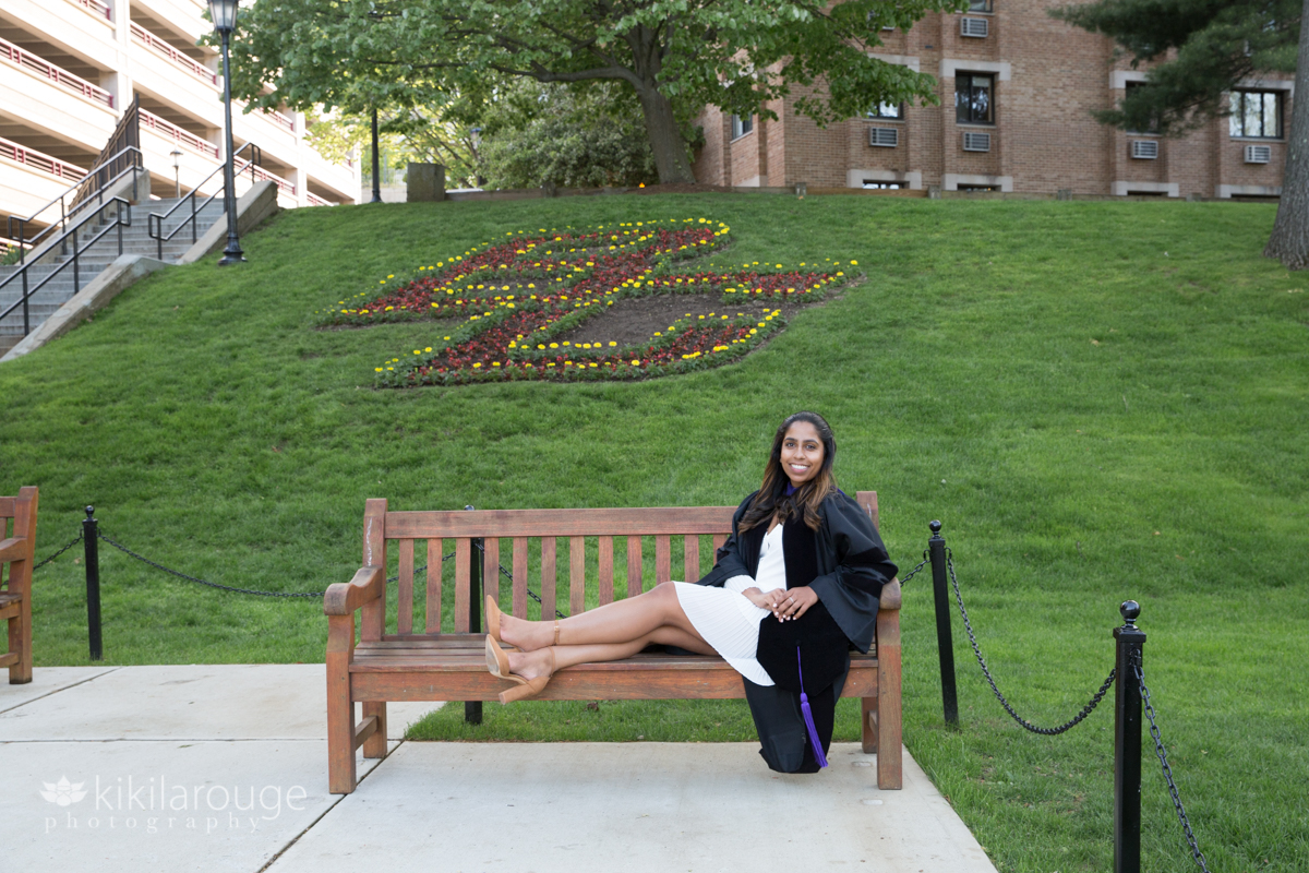 Woman sitting in graduation gown in front of BC landscaped in lawn