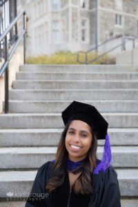 Woman sitting on step is in graduation cap and gown