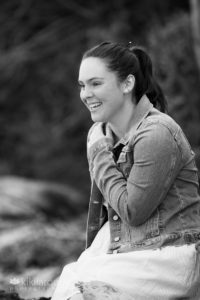 Senior girl in dress and denim laughing at beach
