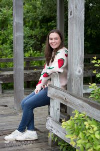Girl sitting on boardwalk with fruit covered sweater