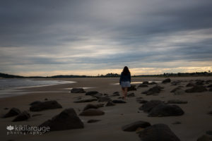 Girl walking away on empty beach with only rocks