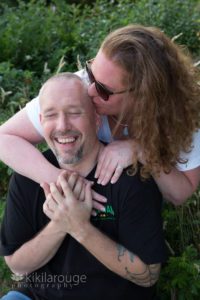 Woman kissing laughing fiancé on beach