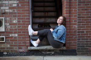 Senior Portrait girl sitting with feet up in brick doorway