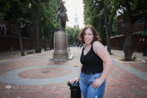 Girl in black top and jeans laughing by Paul Revere statue