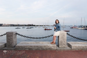 Sunset on Boston harbor with boats and girl in white dress
