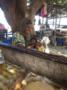 Ugandan woman breastfeeding infant smiling at a picture she is holding