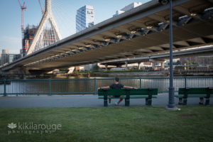 Guy sitting on bench under Zakim Bridge Boston