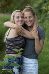 Two sister hugging in grassy field
