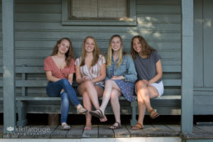 Four young woman sitting on porch together smiling