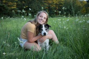 Girl in field of grass and flowers with her rescue dog