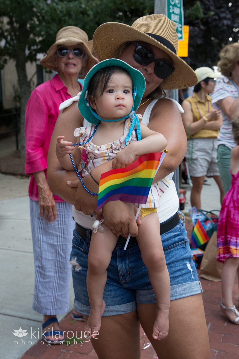 Baby with rainbow flag watching carnival parade