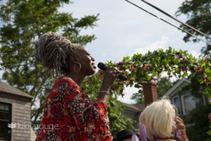 Woman in colorful red dress signing on float