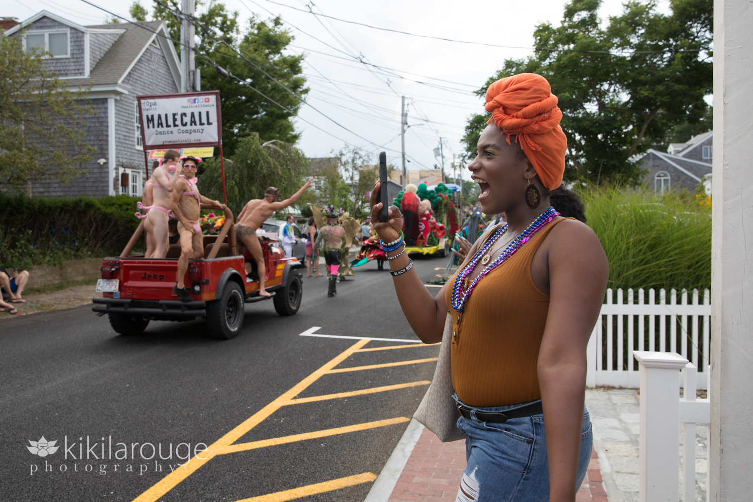 Woman with orange turban smiling and taking a photo at carnival parade