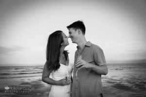 Couple looking at each other at beach with champagne