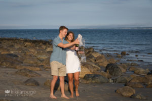 Couple on beach popping champagne celebrating engagement