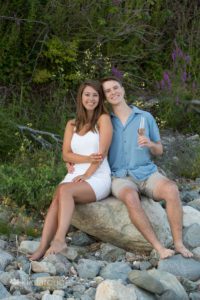 Women white dress with man blue shirt on rocks with champagne