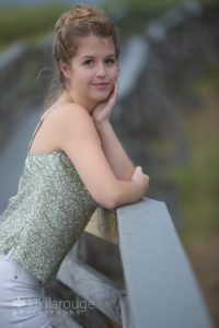 Teen blonde senior leaning on boardwalk post