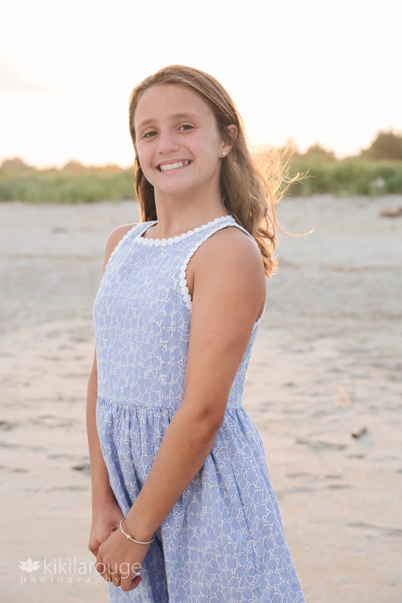 Young girl blue dress big smile with sun flare at beach