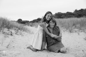 Mom and daughter sitting on dune trail hugging