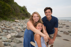 Three siblings by rocks at beach
