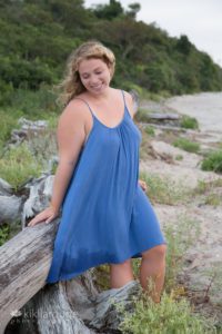 Blonde girl in blue dress windy day at beach