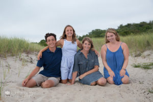 Family portrait of four sitting in beach sand dune