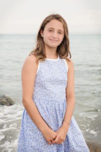 Young girl in blue floral dress by water's edge