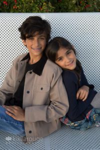 Boy and girl on metal beach back to back smiling