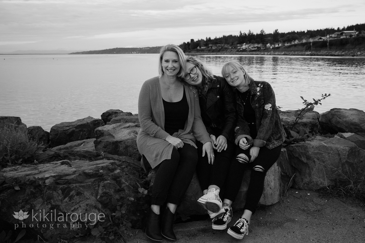Mom with two daughters sitting on rocks at beach