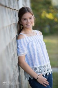 Senior portrait of girl with long hair leaning on wall