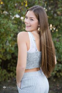 Girl in two piece striped outfit with long brown hair looking over shoulder smiling