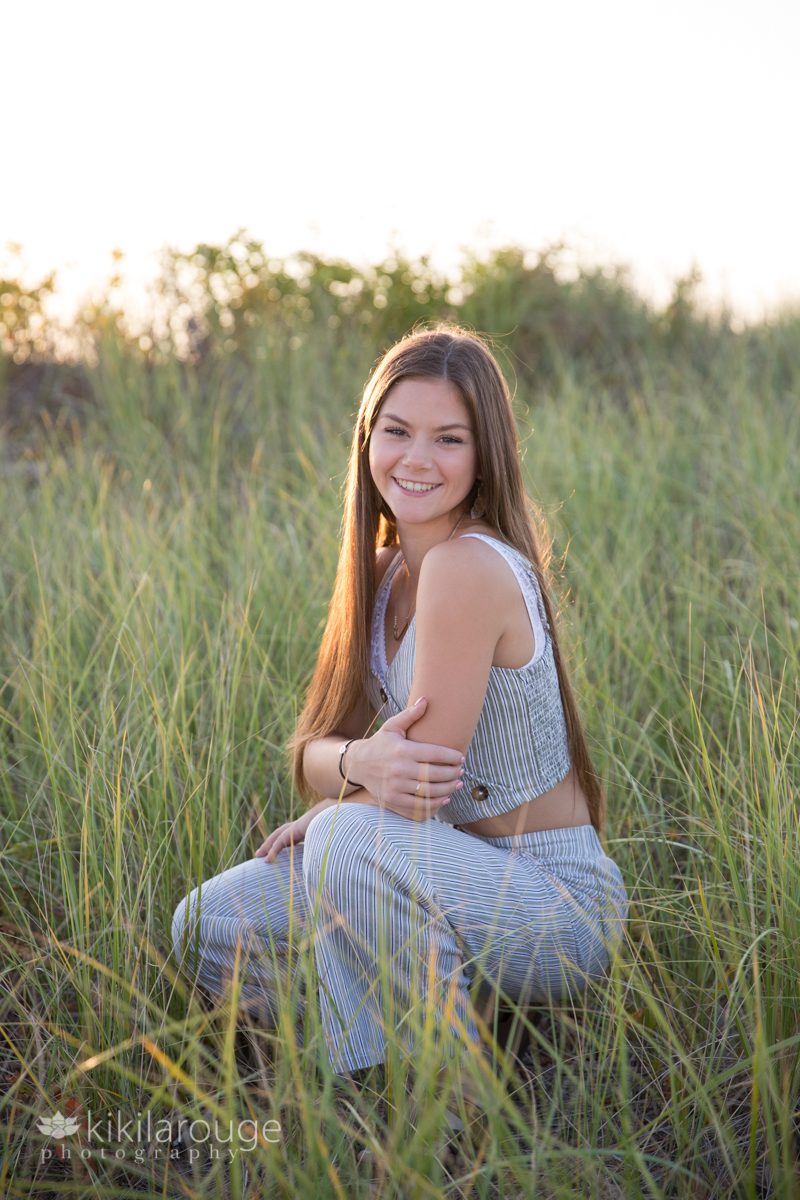 Senior portrait gir in tall dune grass at sunset