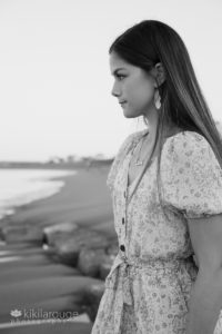 Teen girl long hair in dress on rocks at beach