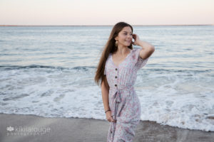 Girl at sunset at beach long hair with hand up looking off in distance